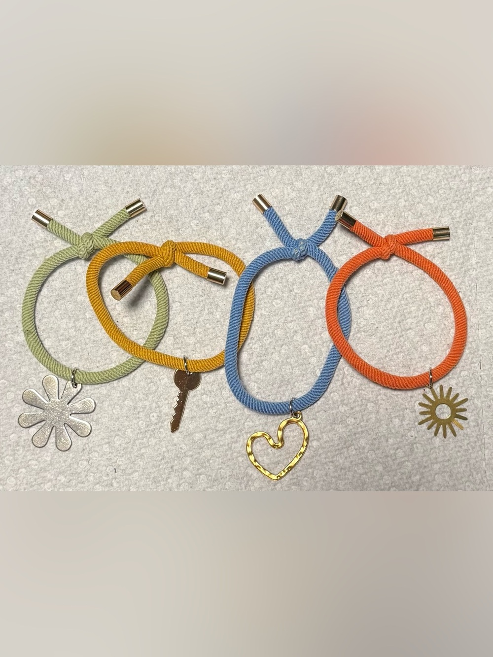 Blue, green, yellow and orange elastic bracelets with gold tone charms.